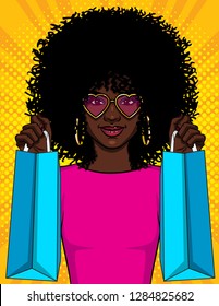 Color style vector illustration of a pop art girl with packages. A beautiful young African American girl holding shopping bags. Happy girl in pink glasses goes shopping. Stylish girl with curly hair 