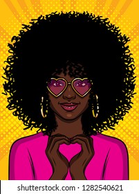 Color vector pop art style illustration of a beautiful african american girl showing with her hands a heart shape. A young woman with pink glasses. Character design for Saint Valentine's day card