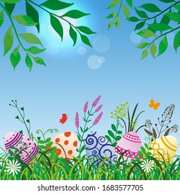 Colored Easter eggs in the grass. Patterned easter eggs on background of sky and branches.