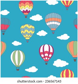 Colored hot air balloons seamless pattern on light blue sky background with white clouds for travel design