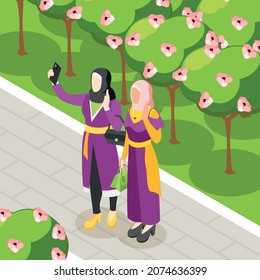 Colored isometric background with two young female person in hijab taking selfie at garden nature vector illustration