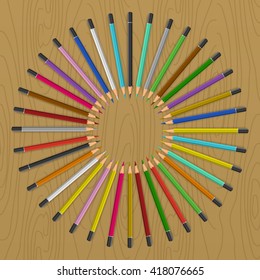 Colored pencils arranged in circle like rays of sun. Color pencils on table.