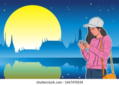 Colorful Asian tourist girl standing and see her smart phone with blue Silhouette temple with stars and full moon