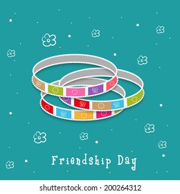 Colorful bangles on floral decorated green background for Happy Friendship Day celebrations. 