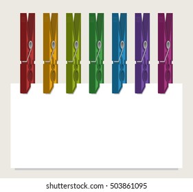 Colorful clothes-pegs holding piece of paper