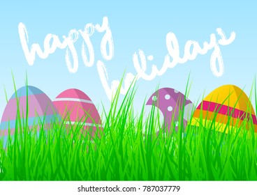 colorful easter eggs in fresh green grass against blue sky with words Happy Easter Holidays greeting card