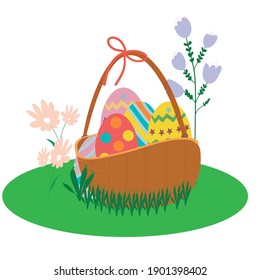 Colorful Easter eggs inside of the basket on a grass and flowers