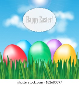 Colorful Easter eggs on green grass on blue sky background and frame for your text
