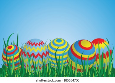 Colorful Easter Eggs on a row in Grass with Blue Sky