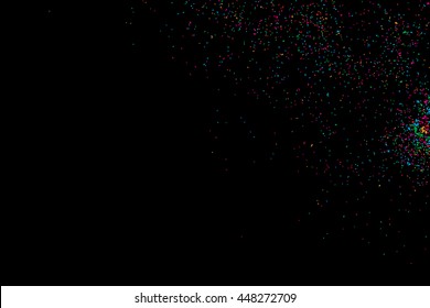 Colorful explosion of confetti. Isolated on black background. Coloured glitter and sprinkles. Grainy abstract holiday illustration. Multi colored texture.