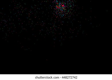 Colorful explosion of confetti. Isolated on black background. Coloured glitter and sprinkles. Grainy abstract holiday illustration. Multi colored texture.