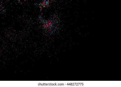 Colorful explosion of confetti. Isolated on black background. Coloured glitter and sprinkles. Grainy abstract holiday illustration. Multi colored texture.