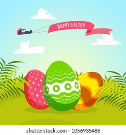 Colorful painted eggs on green ground, with Happy Easter banner. Beautiful nature background.