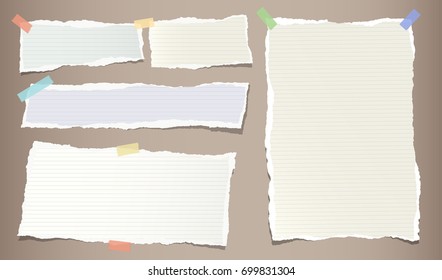 Colorful pastel, ripped note, copybook, notebook paper strips stuck with sticky, adhesive tape on brown background.