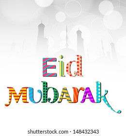 Colorful text Eid Mubarak for Muslim community festival with silhouette of mosque on shiny grey background.
