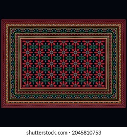 A colorful vintage rug in red shades with large flowers in the center and a patterned border around the edges against a black background.
