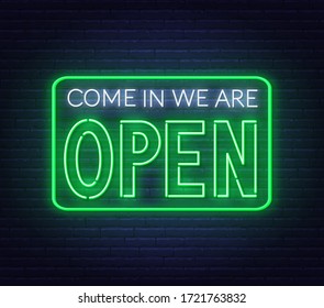 Come in we are open neon sign on brick wall background.