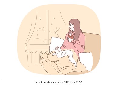 Comfort, rest, cozy relaxation with cat and hot tea in bed at home concept. Young smiling girl drinking tea or coffee in bed, petting cat and relaxing looking at window at home 