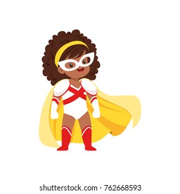 Comic Brave Girl Kid With Curly Hair In Superhero White And Red Costume, Mask And Yellow Cloak, Standing On Legs Wide Apart.