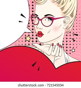 Comic Pop art blonde hair woman send an air kiss in glasses and holds a red heart. Vector illustration.