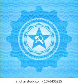 communism icon inside light blue water wave badge background.