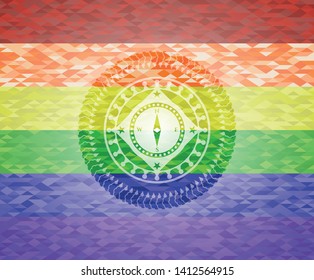 compass icon inside emblem on mosaic background with the colors of the LGBT flag
