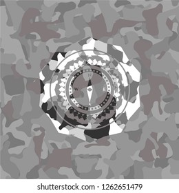compass icon inside grey camouflaged emblem