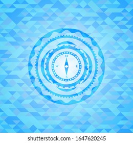 compass icon inside light blue mosaic emblem