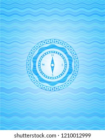 compass icon inside sky blue water emblem.