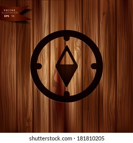 Compass web icon. Wooden background.