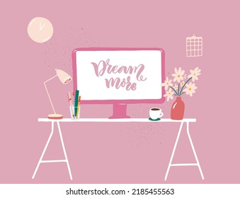 Computer on table at pink feminine interior, cozy workplace with flowers and coffee cup. Hanwritten inspirational quote Dream more on screen.