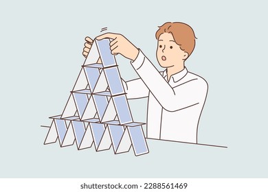 Concentrated man makes pyramid of playing cards symbolizing fragile business structure and unsustainable strategy for development of company. Concept construction of financial pyramids blaming fraud 