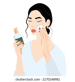 The concept of cleansing and facial skin care. The girl is holding a bottle of makeup remover, toner, mecilar water in her hand. Wipes his face with a cotton pad. Skin care, masking and cosmetics.