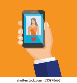 Concept of communication in the network. Hand holding smartphone with female image and heart icon. The concept of activity on social networks. 