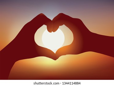 Concept of the declaration of love with two hands forming a heart in front of a sunset.