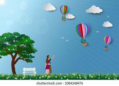Concept of eco friendly save the environment conservation,couple standing in the meadow and looking to hot air balloon flying with tree,paper art and craft design vector illustration
