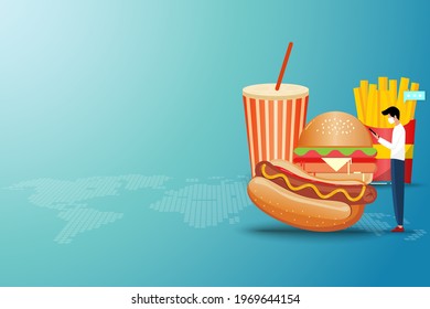 Concept of online fast food delivery service, young man standing in front of a big hamburger to order fast food (sparkling water, hot dog, hamburger and french fries) in green color background.