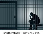 Concept of the prison with the arrest of a criminal. The prisoner is sitting in his cell and desperate, holding his head in his hands.