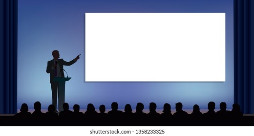 At a conference, a businessman standing behind a desk, points to a white screen to present a project in front of an audience.