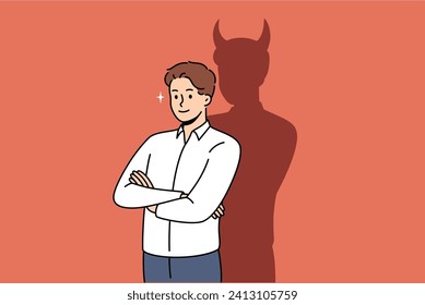 Confident businessman with bad thoughts stands with arms crossed near shadow with devil horns. Bad male office worker with treacherous ideas, wants to achieve goal in unethical way