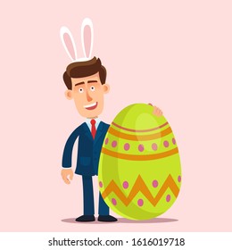 Congratulations on Easter. Smiling man with bunny ears on his head holds big Easter egg. Businessman congratulates a colleagues. Vector illustration, flat design cartoon style, isolated background.