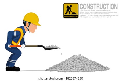 A construction worker is using shovel for scooping the crushed rock.
