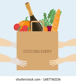 Contactless food delivery: wine, baghe, vegetables. handing a paper bag from hand to hand. Protect yourself from the virus. COVID-19 pandemic.