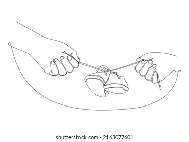 
Continuous line of mother's hand holding baby's shoes