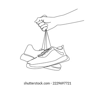 Continuous one line drawing of hand holding sneakers. Fashionable and casual sneakers line art drawing vector design. shoes lineart design.