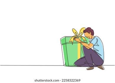 Continuous one line drawing joyful caucasian man hugging huge birthday gift. Young satisfied male sitting near wrapped birthday gift box with bow. Single line draw design vector graphic illustration