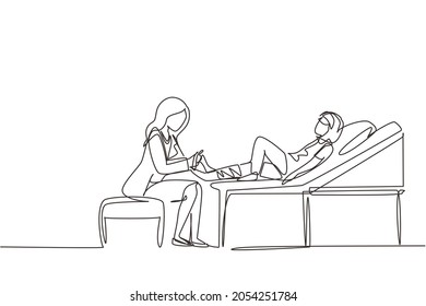 Continuous one line drawing medical doctor bandage broken leg to little girl patient sitting on couch at clinic or traumatology department. Limb fracture. Single line draw design vector illustration