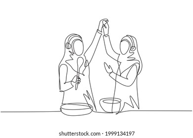 Continuous one line drawing two Arabian woman smiling and dancing with frying pan and spatula in hand while cooking together in kitchen at home. Single line draw design vector graphic illustration