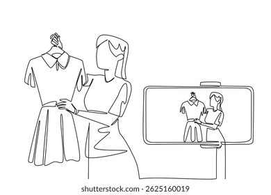 Continuous one line drawing woman holds clothes on a hanger and doing live streaming using a smartphone. Online business. Review. National Streaming Day. Single line draw design vector illustration