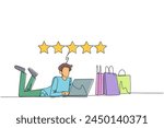 Continuous one line drawing young smiling man on stomach while typing on laptop. Next to the laptop is a shopping bag. Give the best review with pleasure. Single line draw design vector illustration